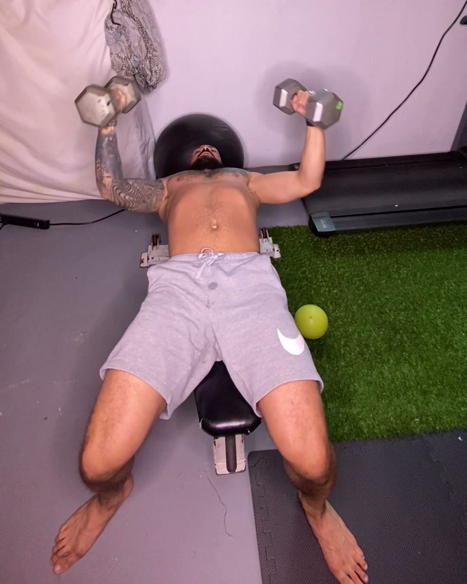 Eddie doing a dumbbell bench press in his home gym