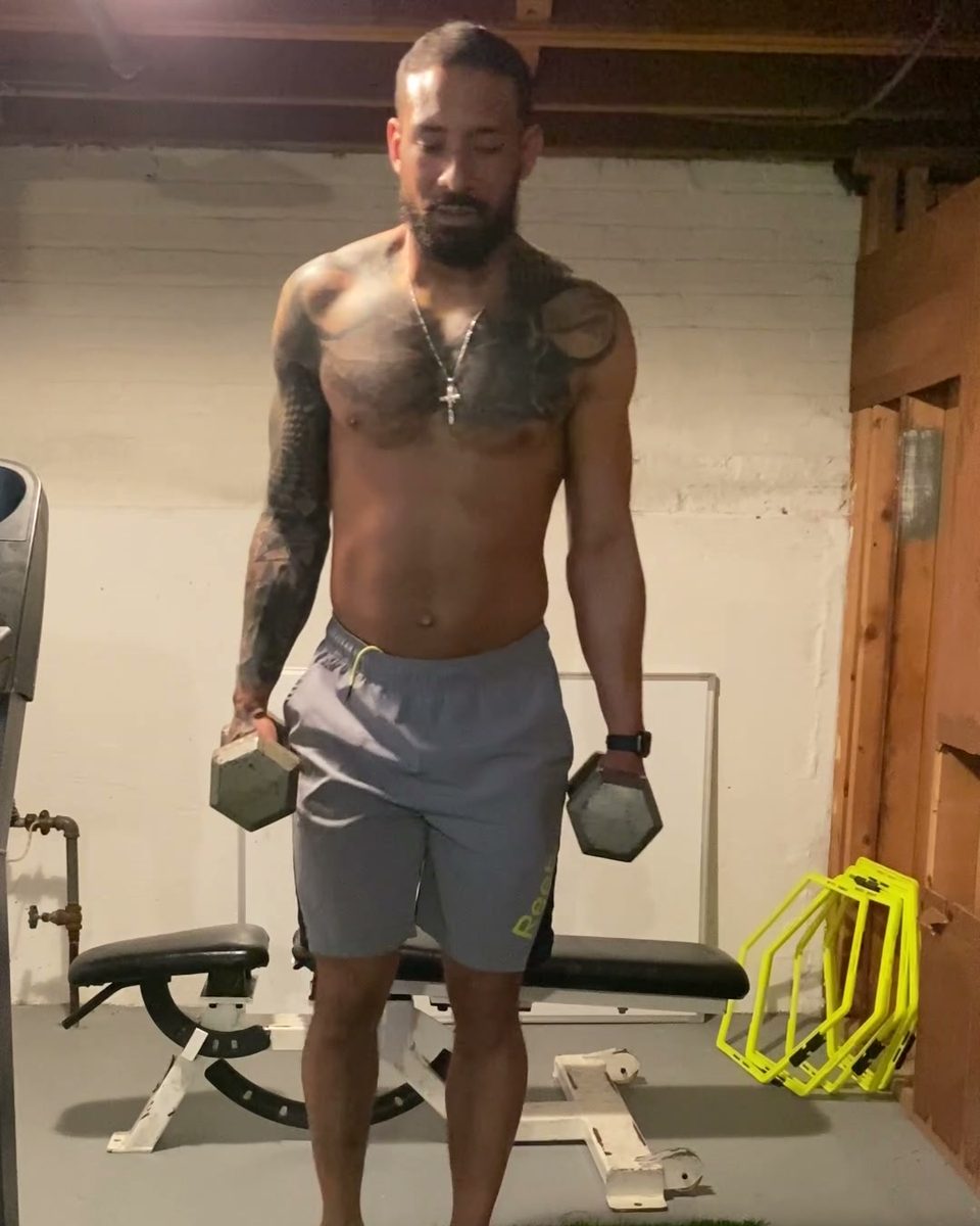 Eddie standing with a dumbbell in each hand in his home gym