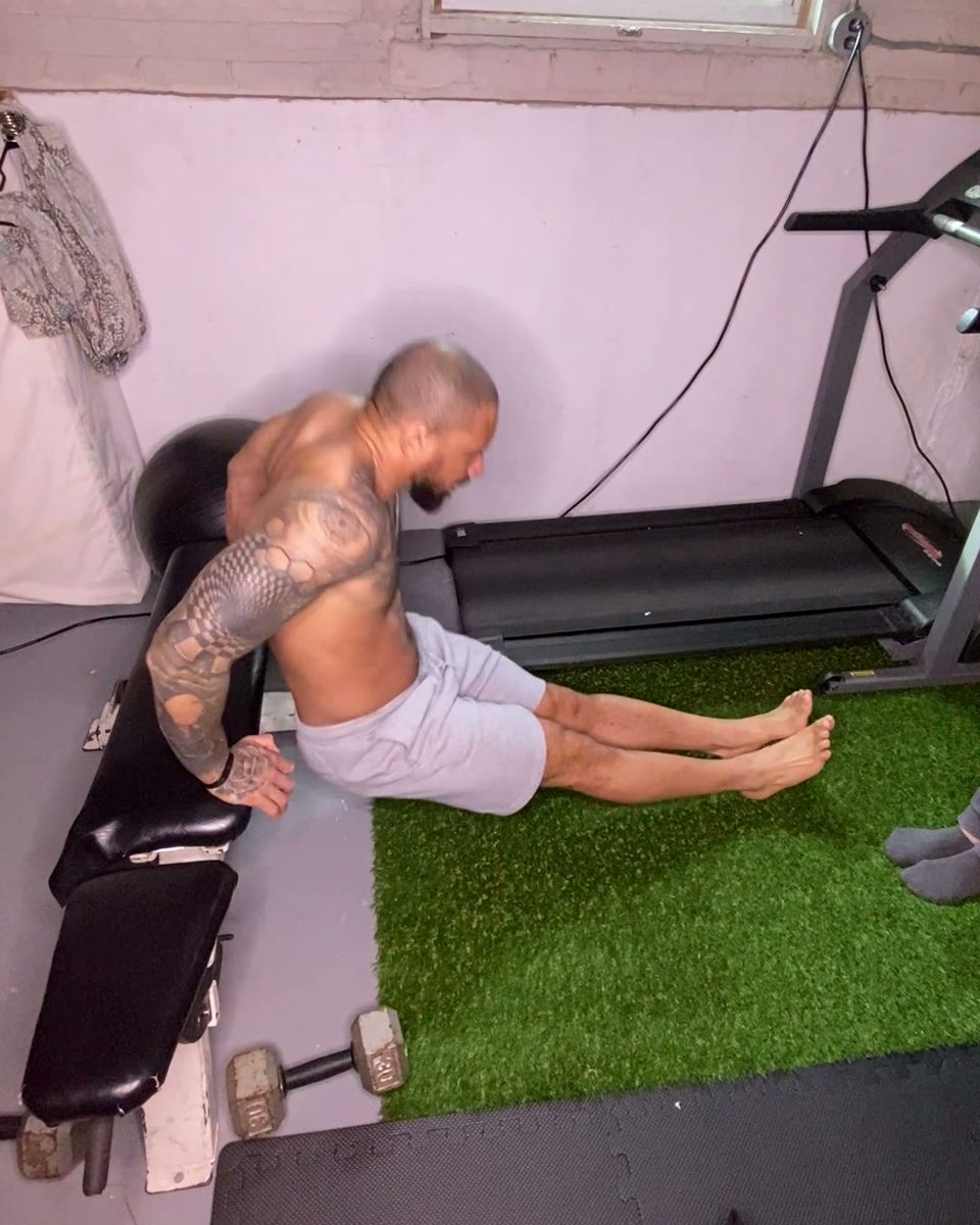 Eddie doing a leg raise on a bench in his home gym